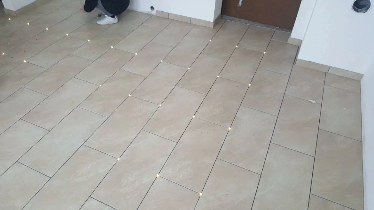 Beige Bodenfliesen mit eingelassenen LED-Spots im Raster