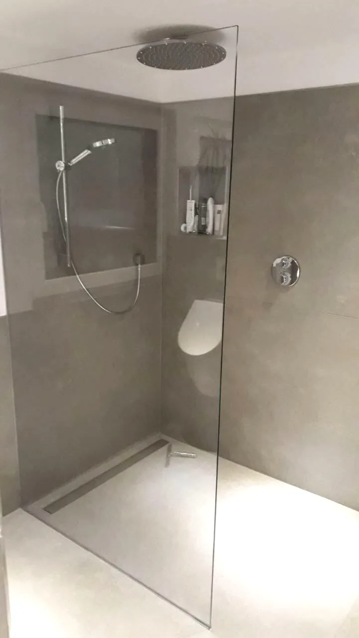 Bodengleiche Dusche mit Regendusche, Glaswand und grauen Wandfliesen