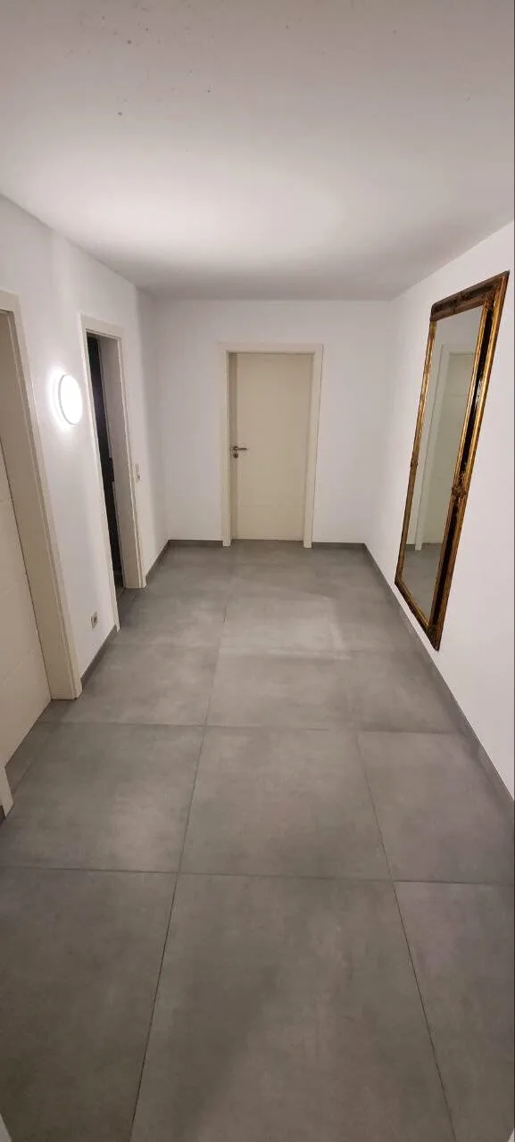 Flur mit grauen Großformat-Bodenfliesen und weißen Türen
