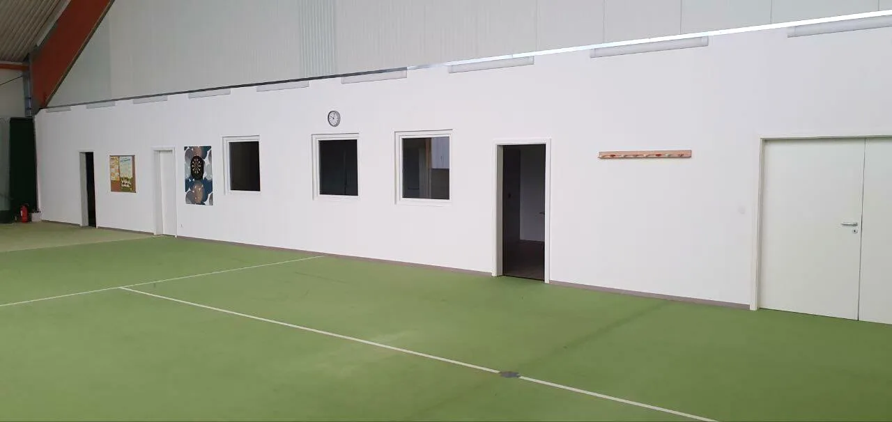 Weiße Trockenbauwand mit Fenstern und Türen in einer Sporthalle
