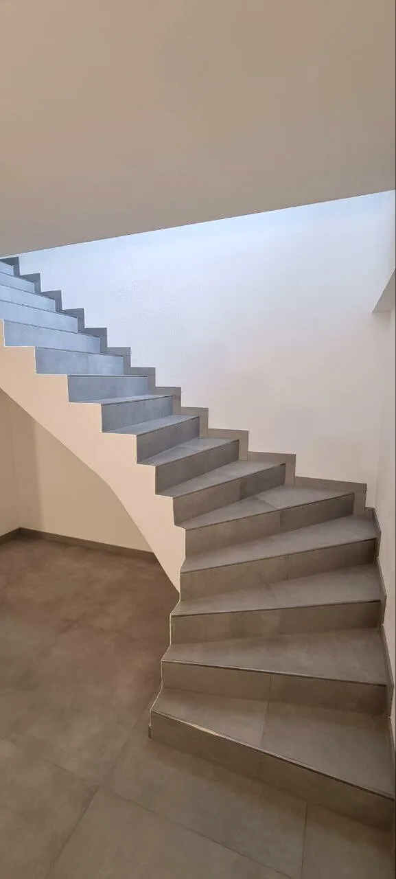Gewendelte Treppe mit Fliesen in Betonoptik