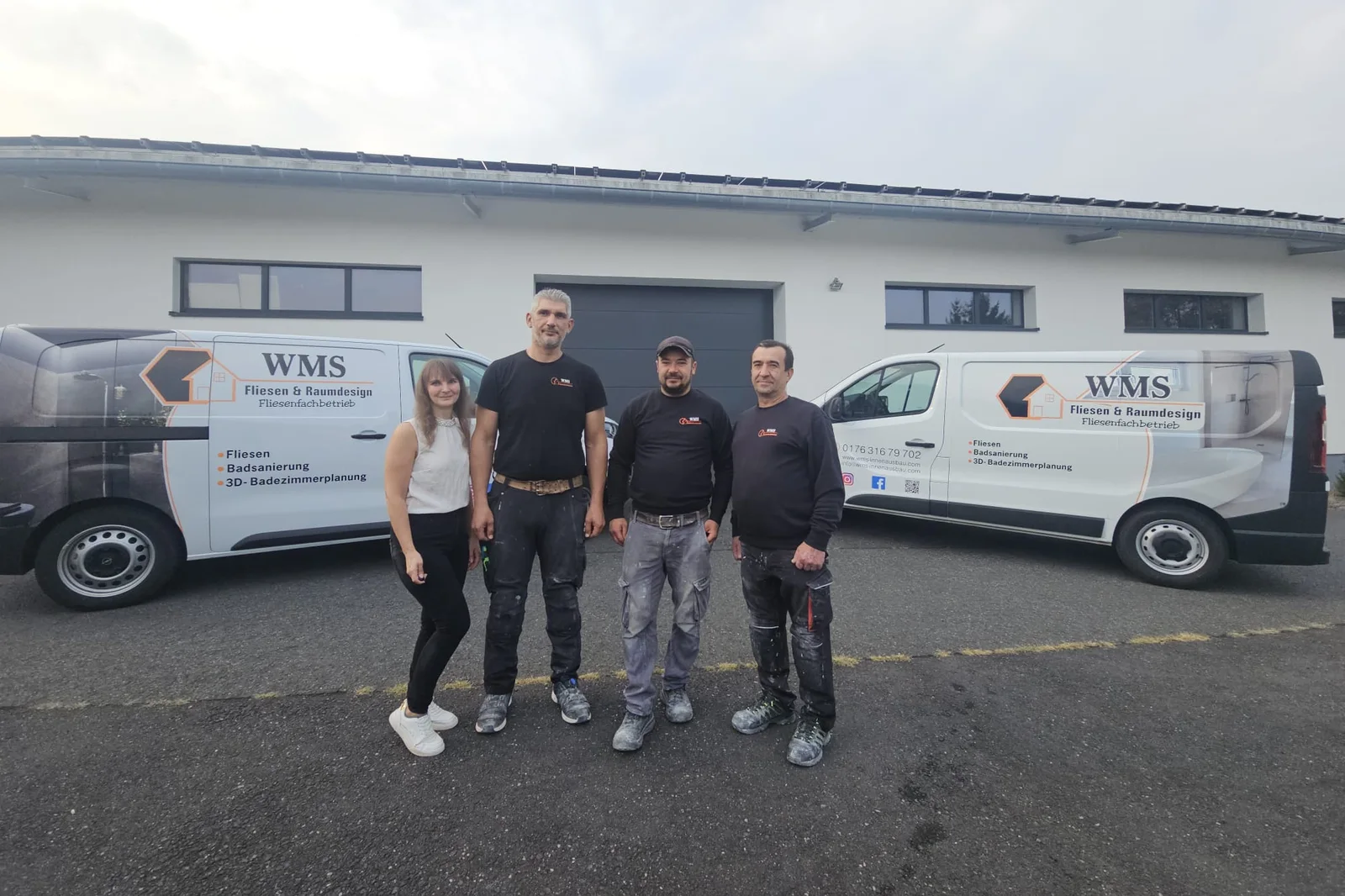 Das Team von WMS Fliesen und Raumdesign vor dem Betrieb in Ulmen mit den beiden beschrifteten Firmenwagen